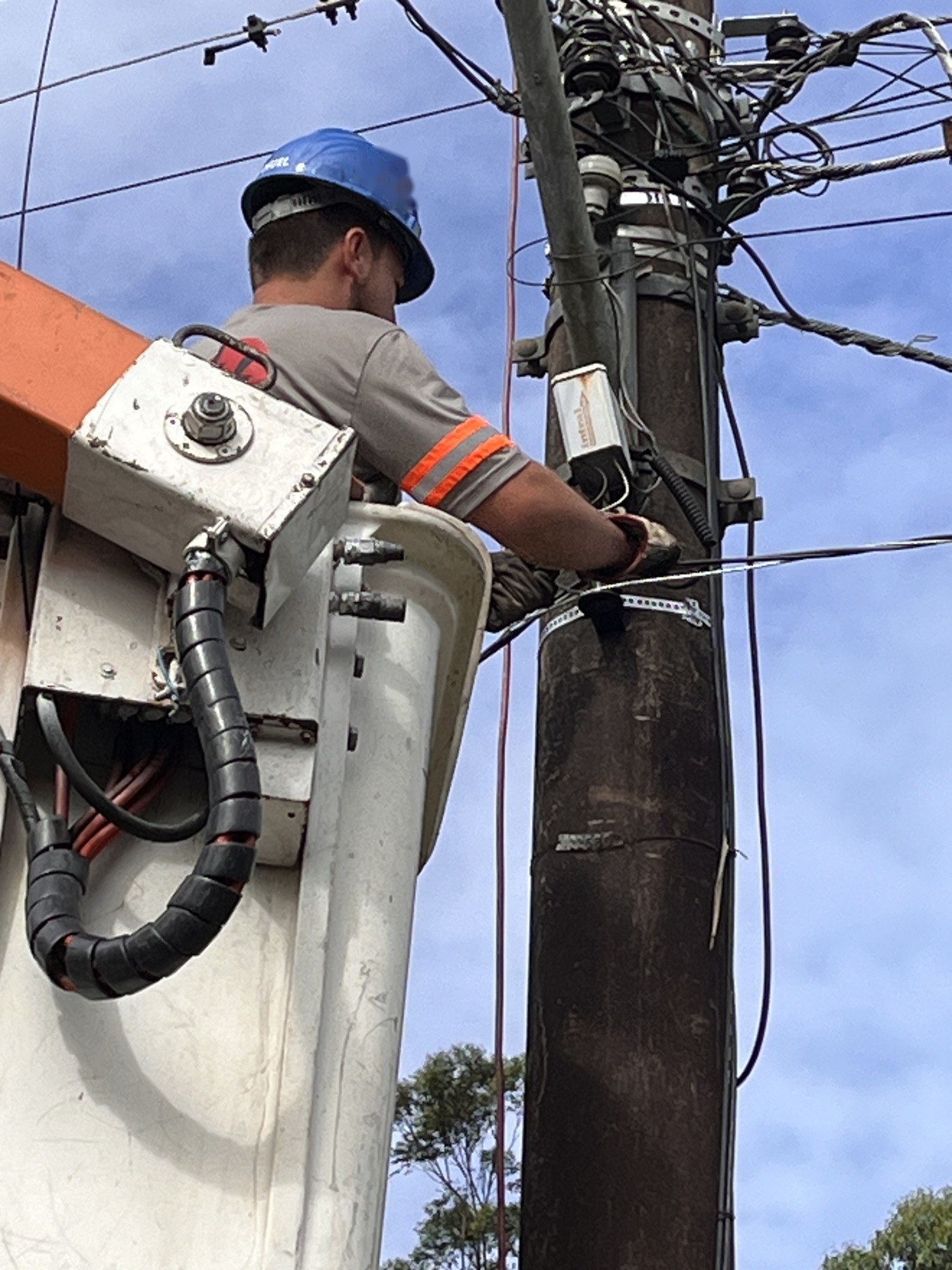 Eletricista com capacete trabalhando em poste
